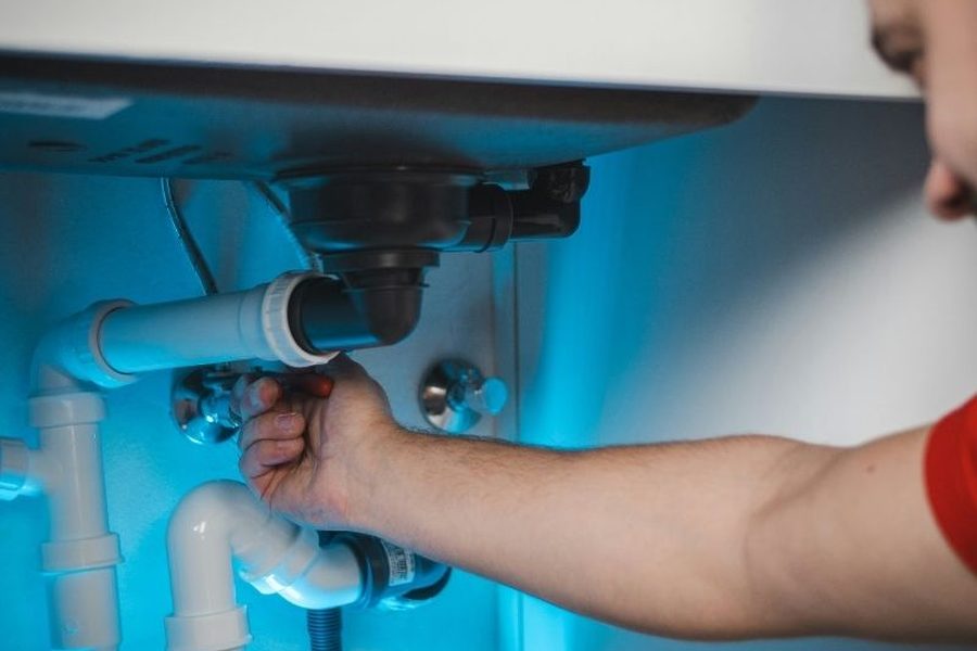 Plumber repairing the drain and shutoff valves under a kitchen sink