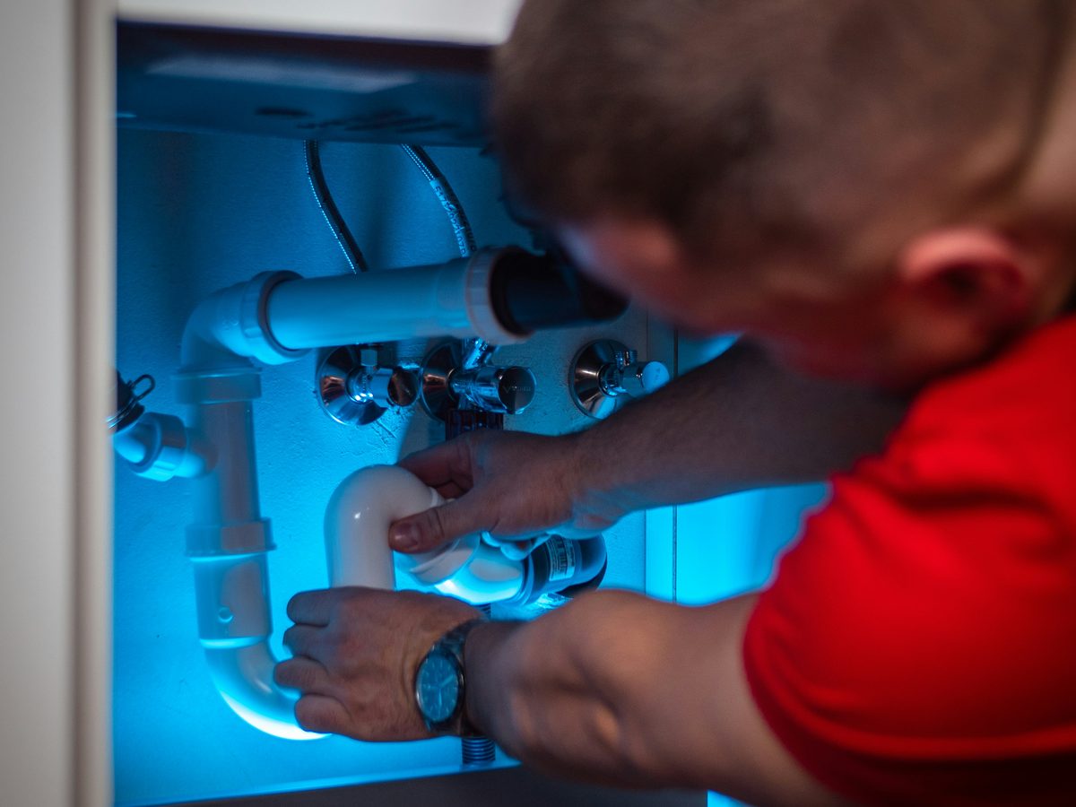 Our plumber working on drain pipework beneath a sink