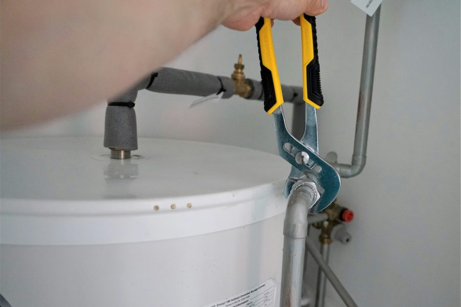Plumber tightening a fitting on a water heater tank